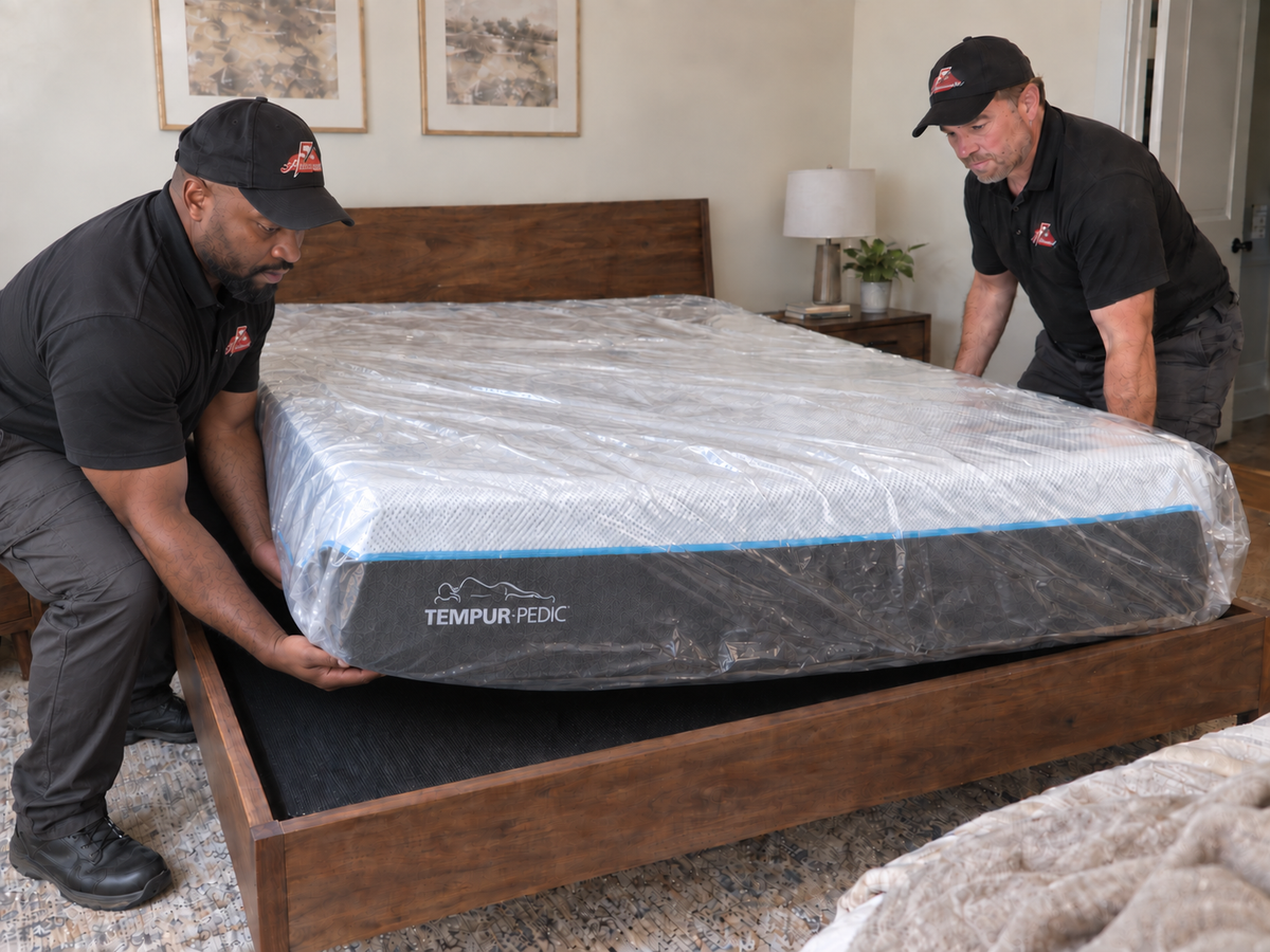 Two delivery professionals positioning a Tempur-Pedic mattress on a bed